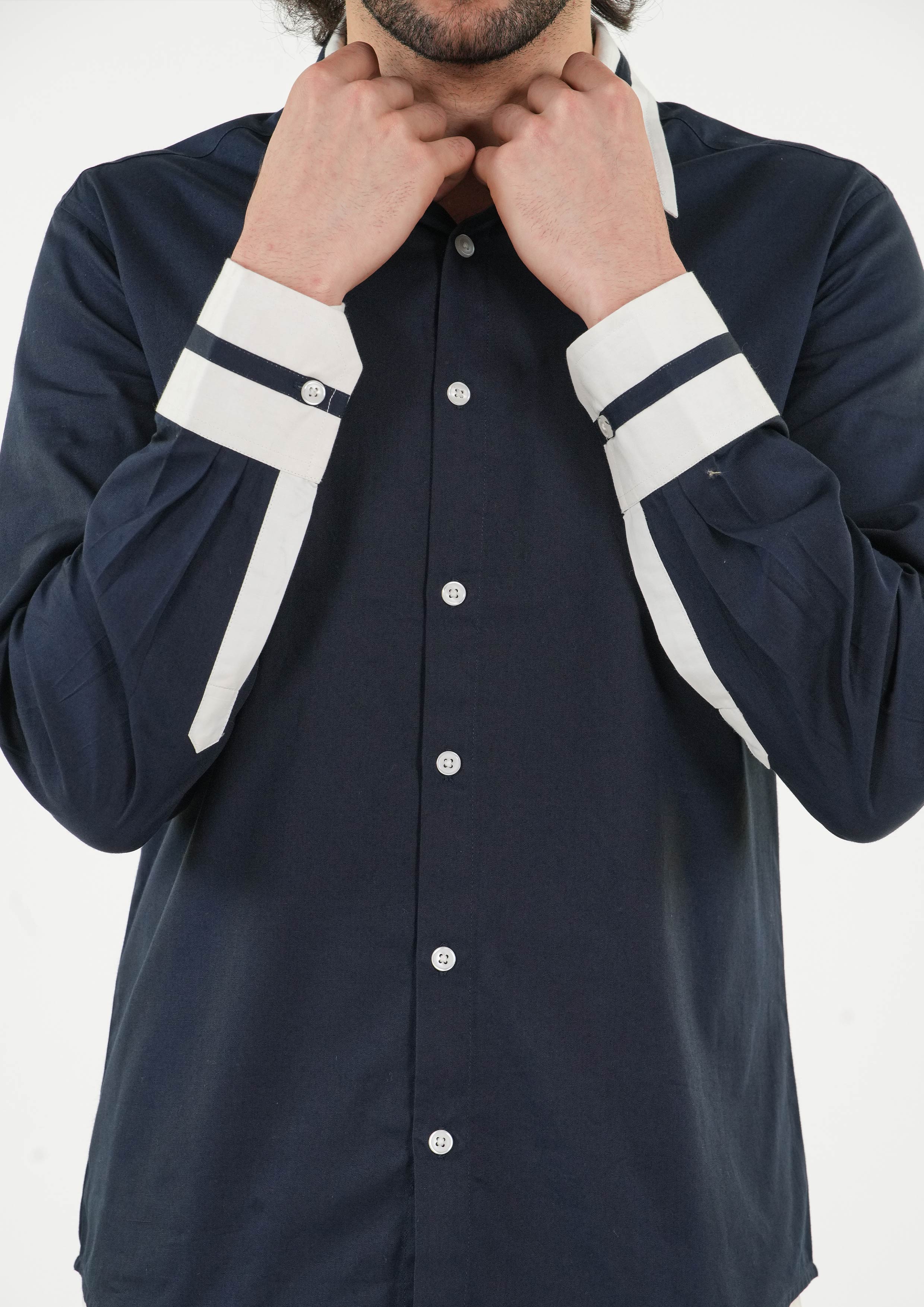 Navy shirt with white trim on sleeves and collar worn by a person against a white background